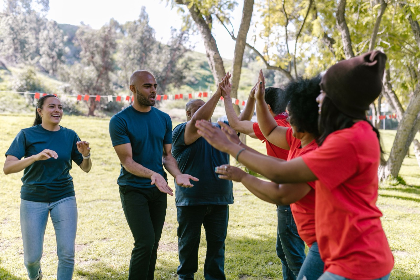 A line of colleagues on grass high-fiving each other at the end of a station.